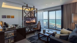 A modern hotel room with a large TV, a desk, a sofa, and a view of the ocean. - The First Collection Marina (Dubai)