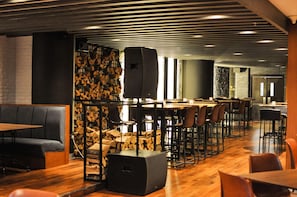 A modern restaurant with a bar area, wooden flooring, and black upholstered seating. - The First Collection Marina (Dubai)