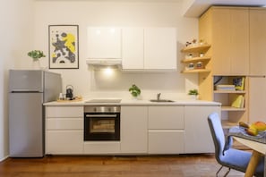A modern kitchen with white cabinetry, a built-in oven, a sink, and a dining area with a chair. - PONTACCIO, 4 - LIVING IN BRERA, IN THE HEART OF MILAN (Milan)