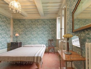 A bedroom with floral wallpaper, a bed with a striped bedspread, a desk with a lamp, and a mirror. - Wonderful private villa for 12 people with WIFI, TV, patio, pets allowed and panoramic view (Scansano)