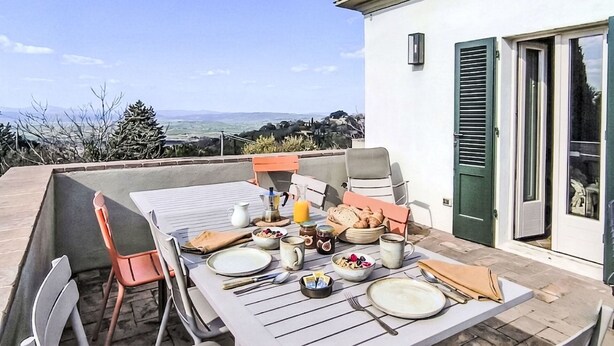 Ein Essbereich im Freien mit einem für das Frühstück gedeckten Tisch, Stühlen und einem schönen Ausblick.