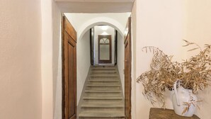 Ein Korridor mit einer Holztür, einer Treppe und einer Tischvase mit Trockenpflanzen.