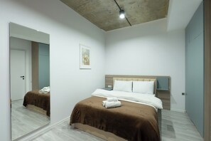 A modern bedroom with a large mirror, a bed with brown bedding, a nightstand, and a framed picture on the wall. - Bright 1BR apartment in Avlabari (Tbilisi)