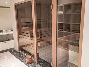 Ein modernes Badezimmer mit einer gläsernen Duschkabine, einer hölzernen Sitzbank und einem Marmorboden.