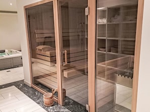 Ein modernes Badezimmer mit einer gläsernen Duschkabine, einer hölzernen Sitzbank und einem Marmorboden.