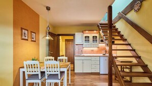 A kitchen with wooden cabinets, a dining area with white chairs, and a wooden staircase. - Beautiful apartment for 4 guests with WIFI and TV (Turnov)
