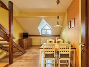 Acogedor cuarto ático con mesa y sillas, televisor y ventana con vista.