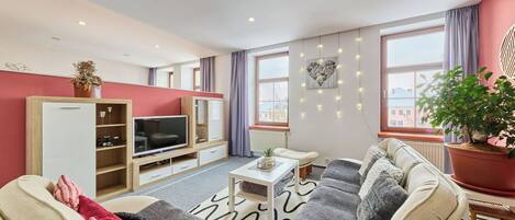 Una sala de estar moderna con televisión, sofá y un ventanal grande.