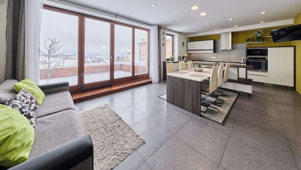 A modern apartment with a dining area, kitchen, and large windows offering a view of a snowy landscape. - Cosy apartment for 6 guests with WIFI, TV and terrace (Turnov)