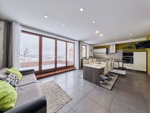 A modern apartment with a dining area, kitchen, and large windows offering a view of a snowy landscape. - Beautiful apartment for 6 guests with WIFI, TV and terrace (Turnov)