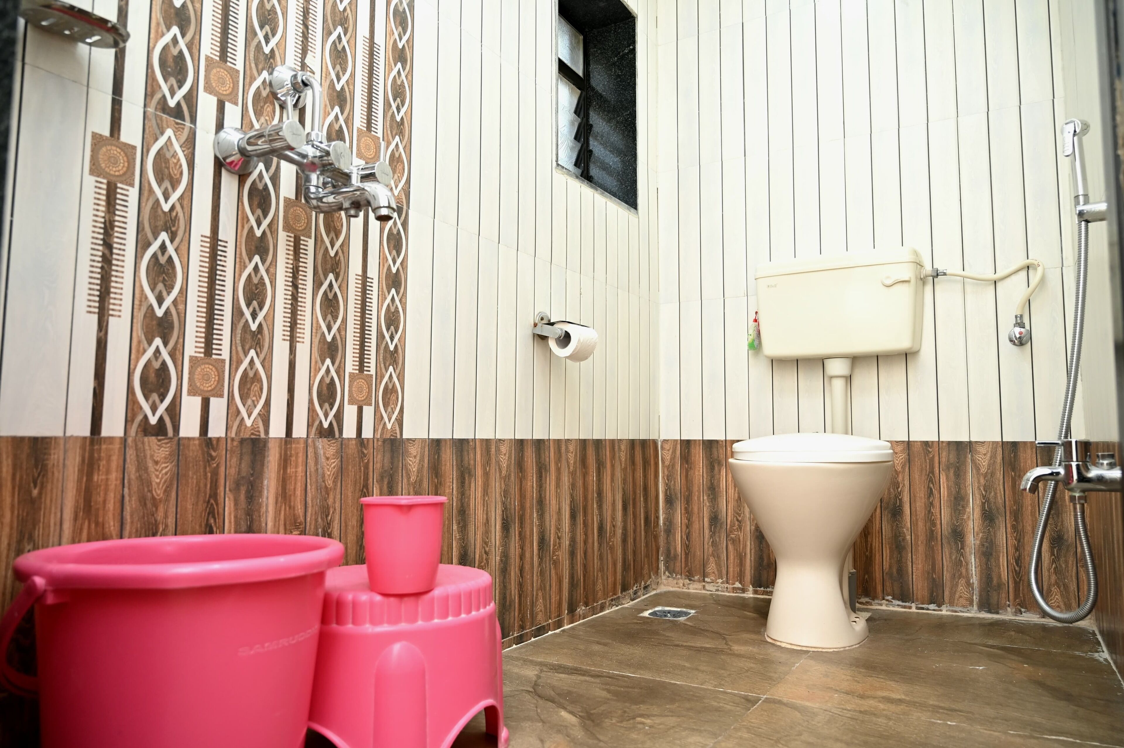 A bathroom with a toilet, bidet, and pink buckets.