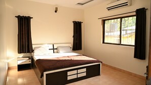 Ein Schlafzimmer mit einem Bett, Nachttischen, einem Fenster und einer Klimaanlage.