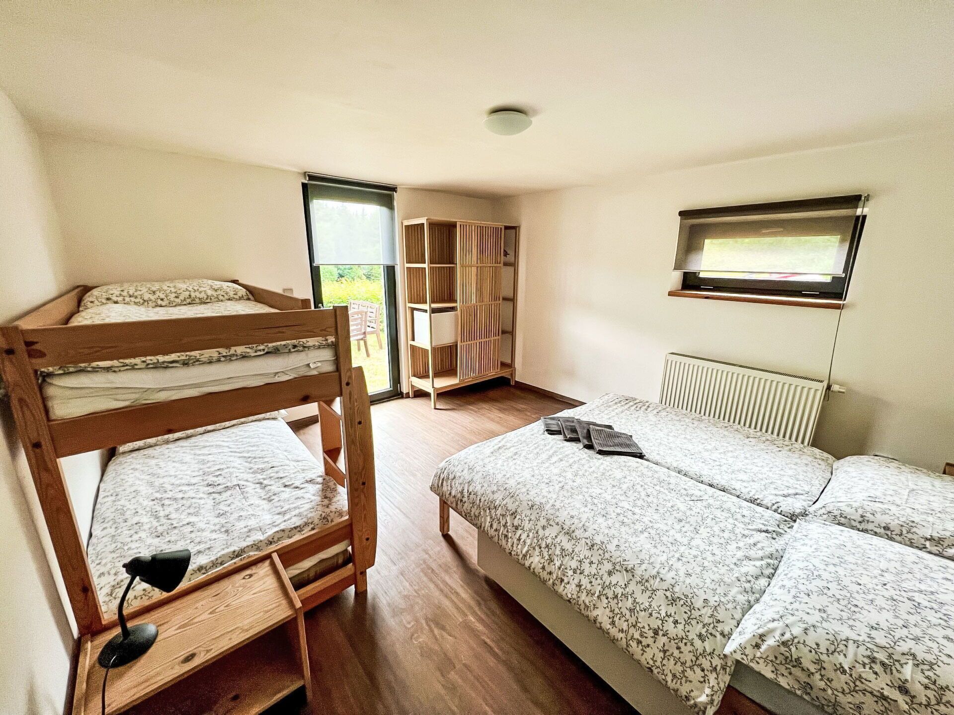A room with bunk beds, a desk, a chair, a bookshelf, and a TV.