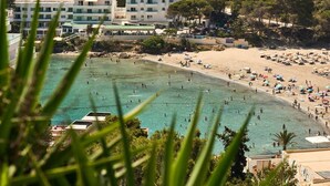 A coastal area with a swimming pool, beach, and buildings in the background. - Studio 2 (Cala Llonga)