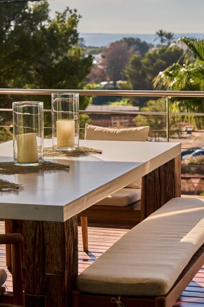 Un balcón con una mesa para dos, con velas y vistas al océano.