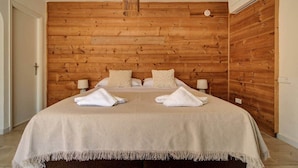 Ein Hotelzimmer mit Holzpaneelen, einem Bett mit weißer Bettwäsche, zwei Nachttischlampen und einer Hängeleuchte.