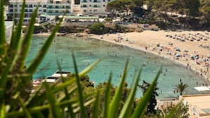 Eine Küstenlandschaft mit Schwimmbad, Strand und Gebäuden im Hintergrund.