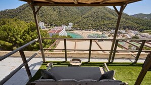 Um deck de madeira com um sofá e uma mesa, com vista para a praia e edifícios.