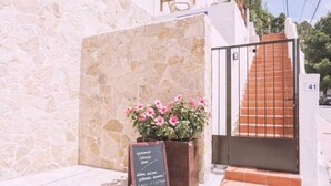 A stone wall, a flower planter, a signboard, and a staircase with a metal gate. - Apartment nº7, 1 bedroom, 1 bathroom (Cala Llonga)
