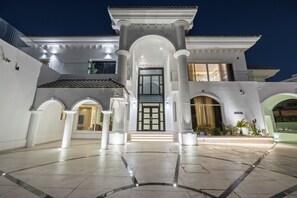 A grand entrance with a central archway, a large door, and a well-lit pathway leading to the main building. - Luxury Villa with Pool- Cinema and Spa  (Dubai)