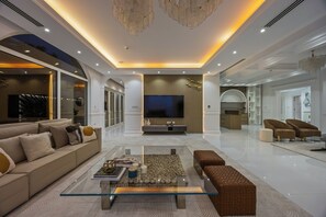 A modern living room with a glass coffee table, beige sofa, and brown ottomans. - Luxury Villa with Pool- Cinema and Spa  (Dubai)