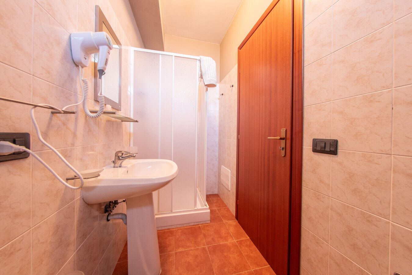 A bathroom with a sink, a hairdryer, and a shower.