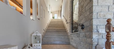 A staircase with stone steps leading to a room with a stone wall and a wooden ceiling.