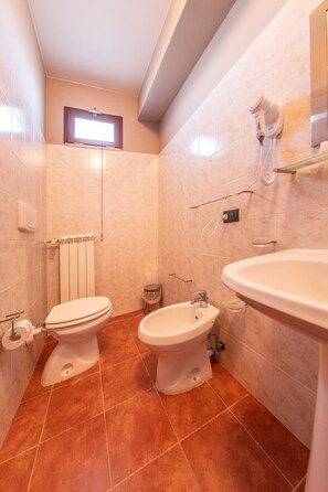 A bathroom with two toilets, a bidet, a sink, and a hairdryer on the wall. - Tenuta Giave - Camera Matrimoniale 2 (Montemarano)
