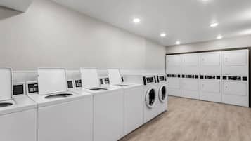 Un moderno cuarto de lavandería con varias lavadoras y secadoras, piso de madera y un diseño limpio y minimalista.