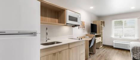 Una kitchenette equipada con microondas, pileta y refrigerador.