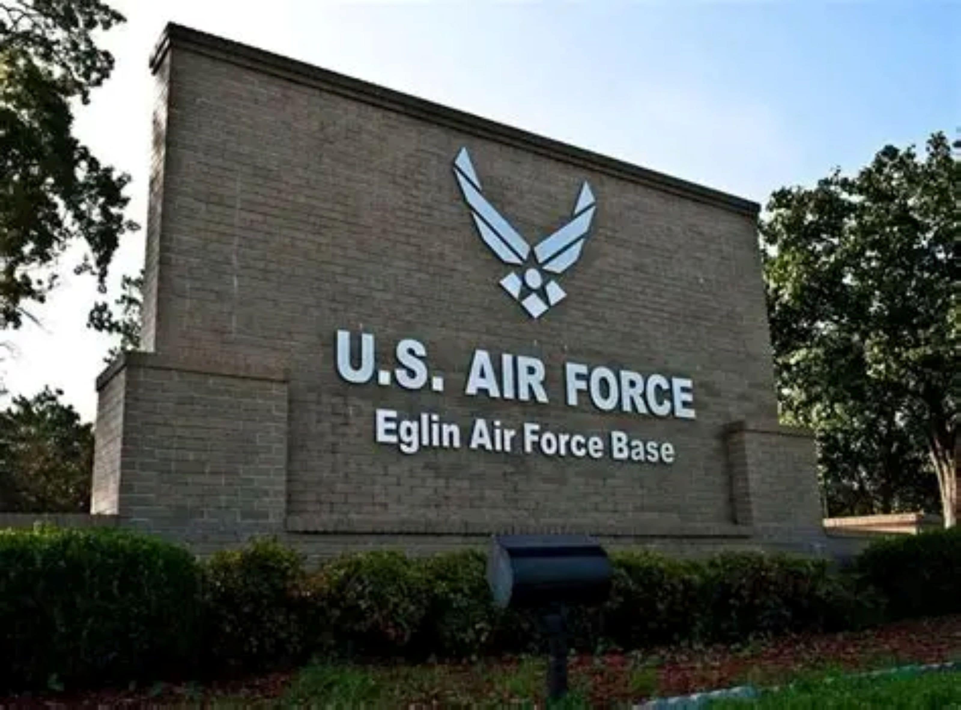 Un panneau indiquant la base de l’armée de l’air américaine, avec un logo et le nom « Base de l’armée de l’air d’Eglin », sur un mur de briques.