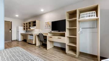 Une pièce moderne et bien éclairée, dotée d’une kitchenette, d’un bureau avec une chaise et d’étagères intégrées.