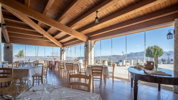 Un restaurant amb bigues de fusta, grans finestres i taules preparades per dinar.