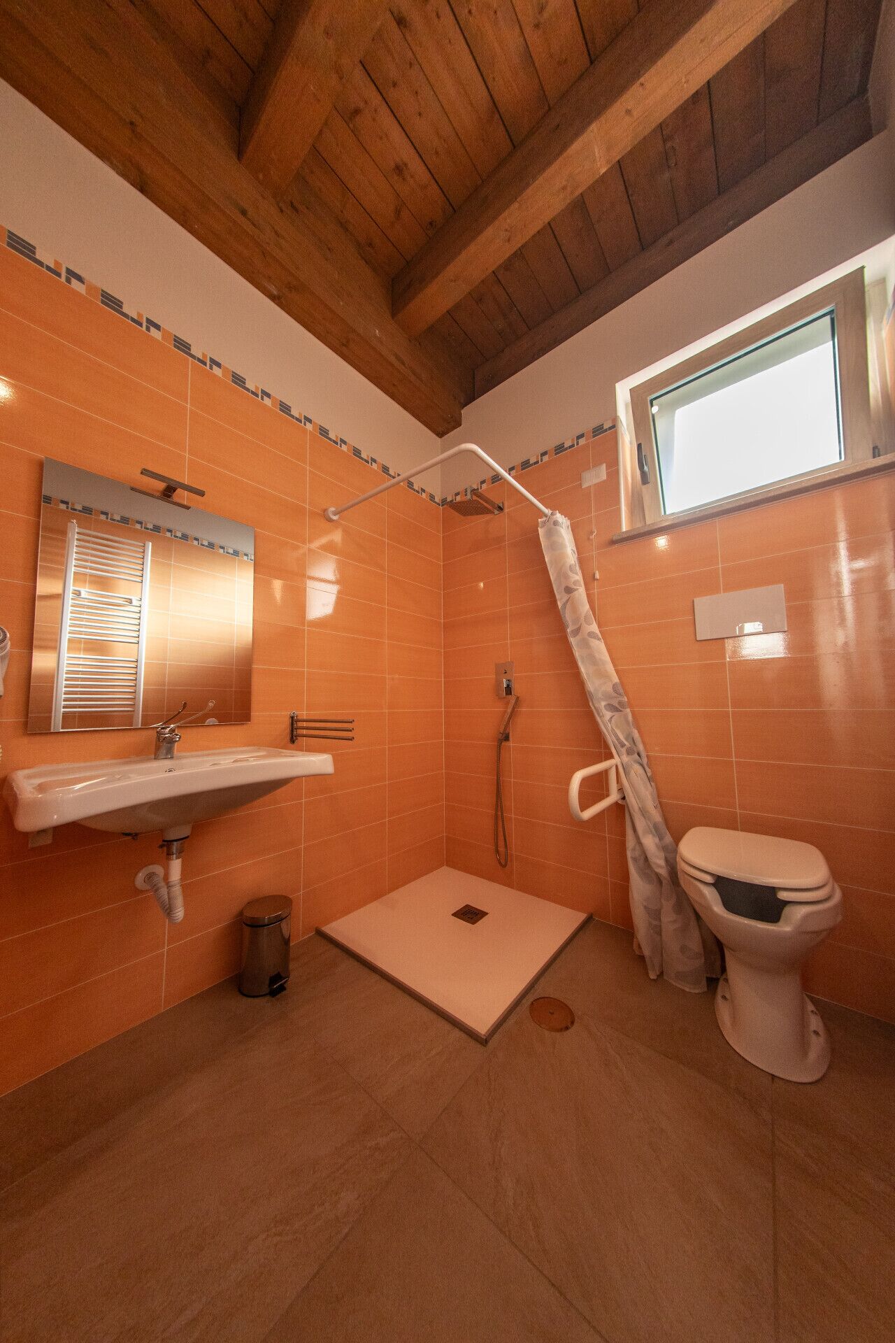 A small bathroom with a shower, a sink, and a toilet.