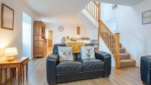 A living room with a leather sofa, wooden cabinet, and a staircase. - Wonderful private villa for 4 guests with WIFI, TV and pets allowed (Inverness)