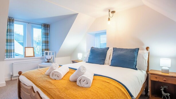 A bedroom with a bed, two bedside tables, a nightstand, a window with curtains, a radiator, and a wall-mounted light fixture. - Wonderful private villa for 4 guests with WIFI, TV and pets allowed (Inverness)