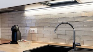 A modern kitchen with a black sink, a coffee maker, and a glass bowl on the counter. - Cosy apartment for 2 people with A/C, WIFI and balcony (Sanremo)