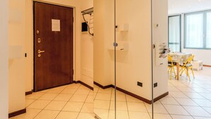 A hotel room with a wooden door, a glass partition, a tiled floor, and a dining area with yellow chairs and a table. - Cosy apartment for 2 guests with WIFI, patio, pets allowed and panoramic view (Como)