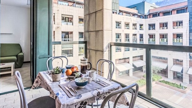 A balcony with a table set for dining, chairs, and a potted plant. - Cosy apartment for 2 guests with WIFI, patio, pets allowed and panoramic view (Como)