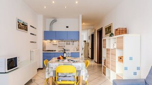 A compact kitchen with blue cabinets, a dining table with yellow chairs, and a white cabinet with storage. - Cosy apartment for 2 guests with WIFI, patio, pets allowed and panoramic view (Como)