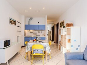 Eine kompakte Küche mit blauen Schränken, einem Esstisch mit gelben Stühlen und einem weißen Schrank mit Stauraum.