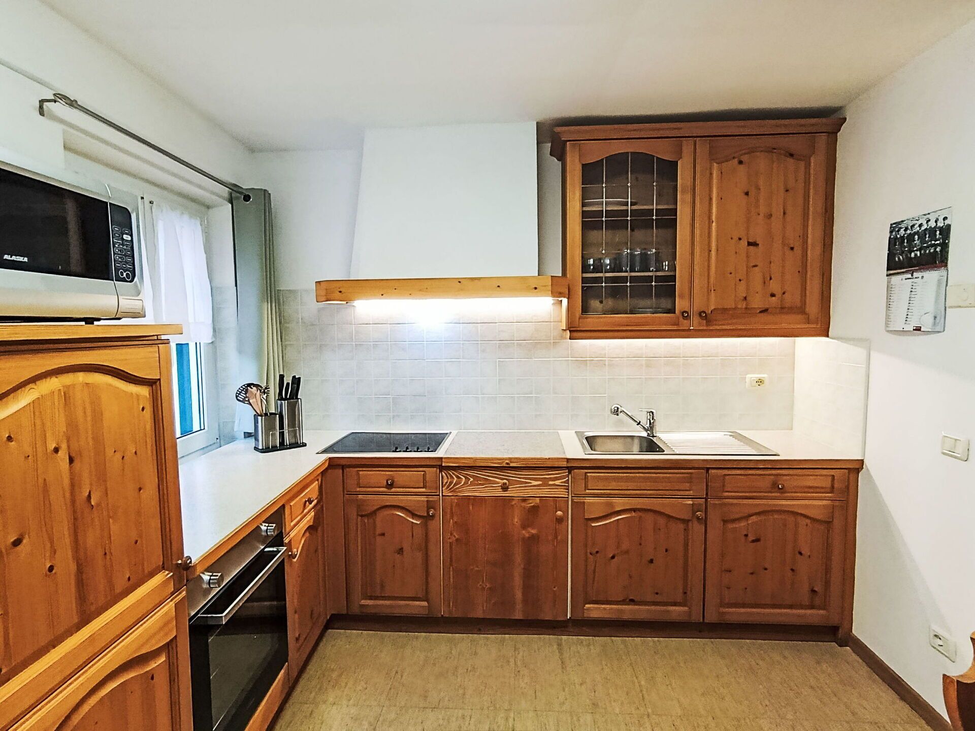 Cocina con armarios de madera, microondas, estufa y fregadero.