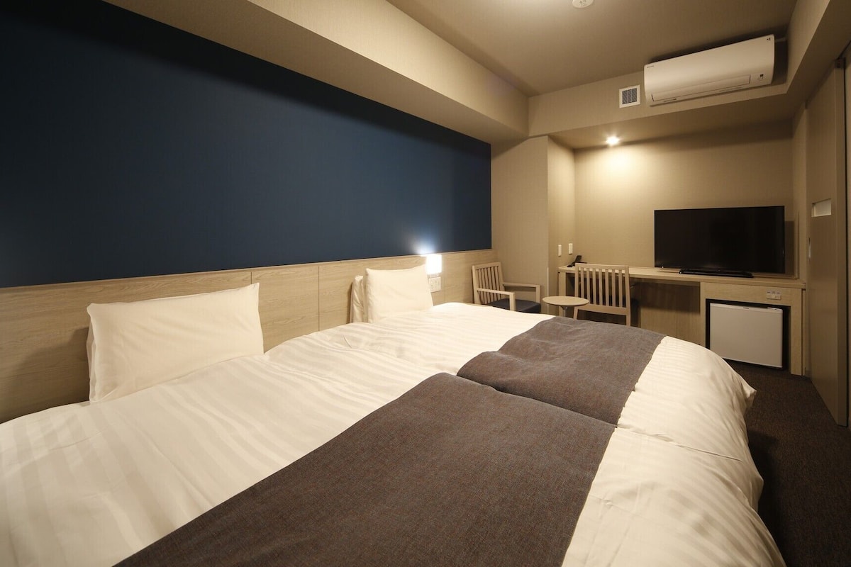 Ein Hotelzimmer mit einem großen Bett, einem Schreibtisch mit Fernseher und einer Klimaanlage.