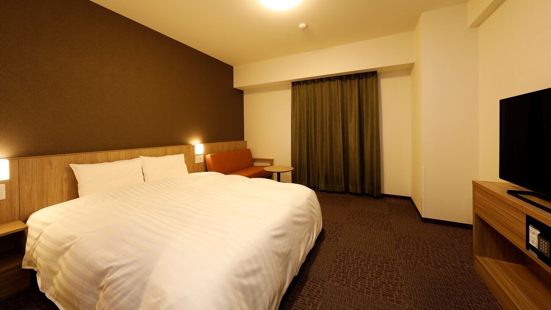 A hotel room with a large bed, a television, a desk, and a chair.