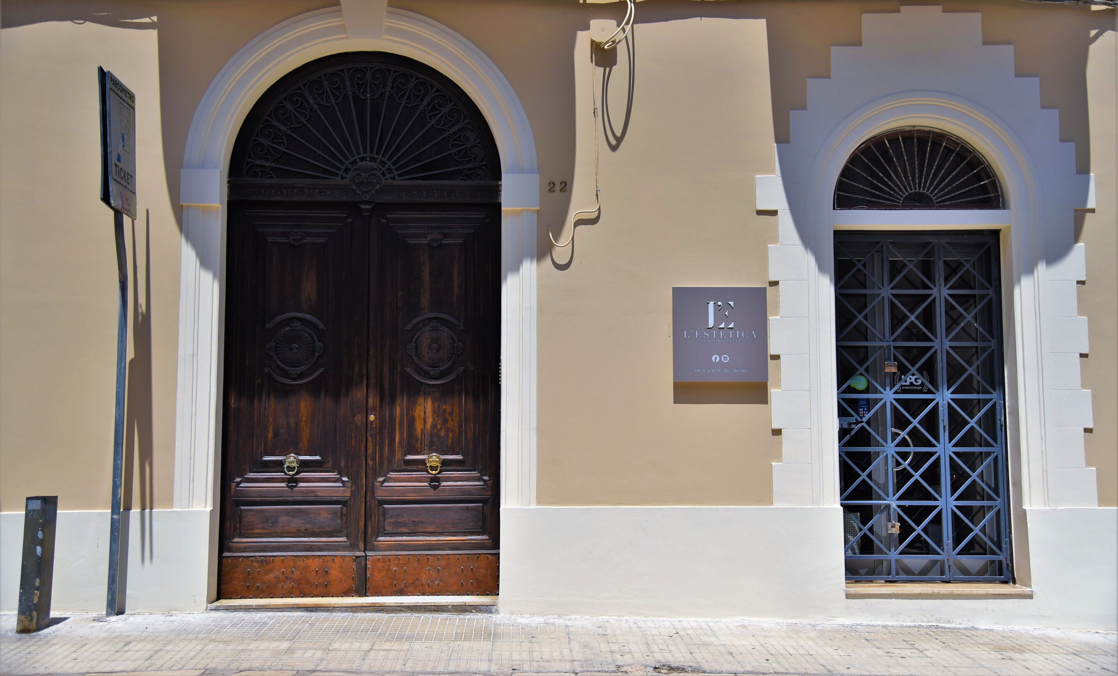 A building facade with two large wooden doors and a smaller window with a blue grille.