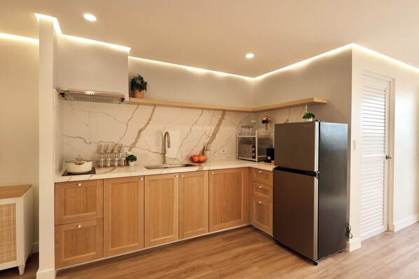Uma cozinha moderna com armários de madeira, painel de fundo de mármore e geladeira de aço inoxidável.