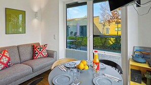 Ein modernes Wohnzimmer mit einer Couch, einem Esstisch und einem Fernseher.