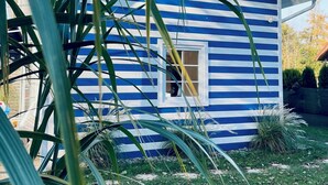 A blue and white striped house with a visible window and a door. - House with 2 bedrooms near of the forest and sea. (Województwo pomorskie)