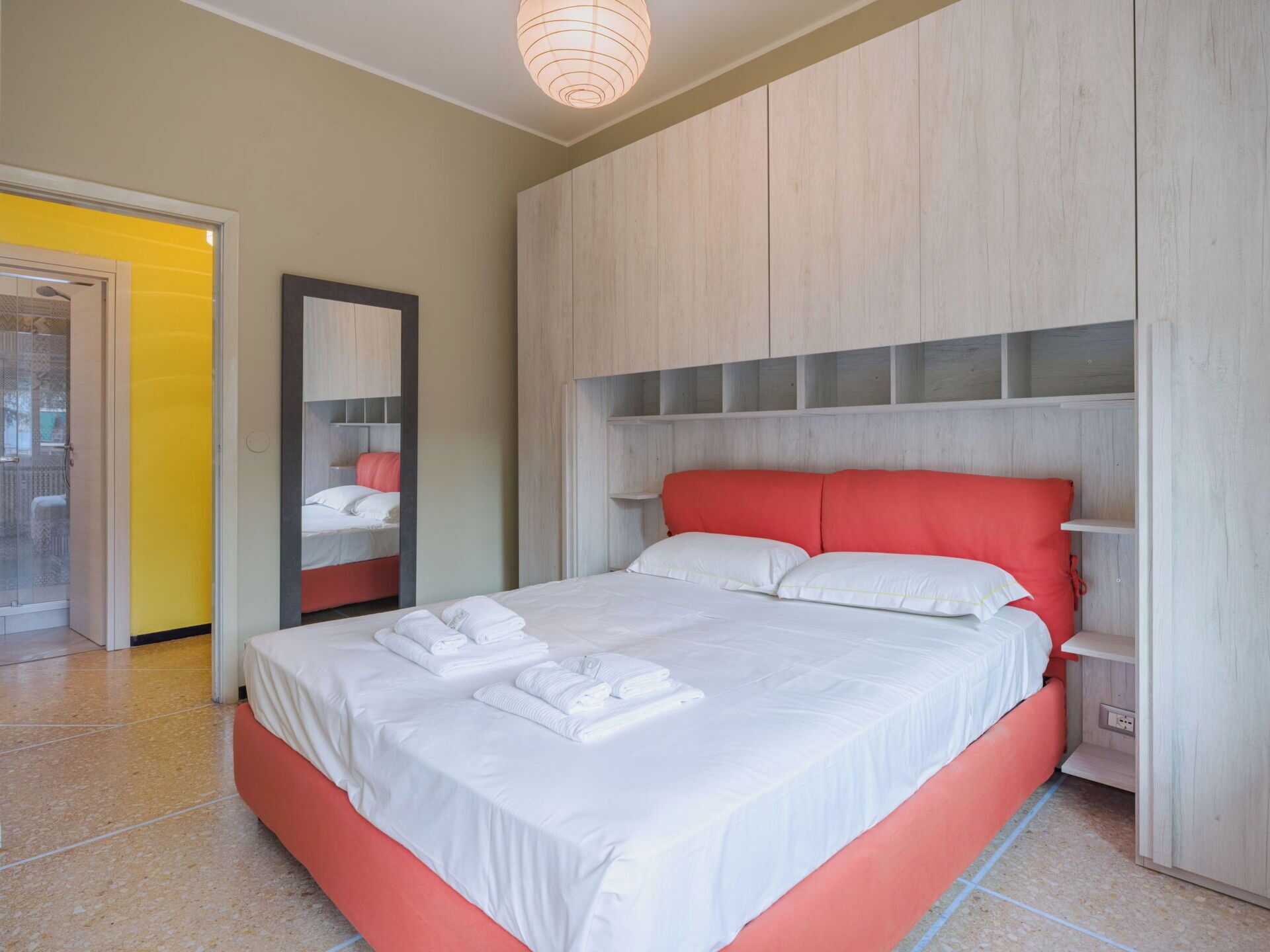 Ein modernes Hotelzimmer mit einem großen Bett, einem Spiegel und einem Holzschrank.