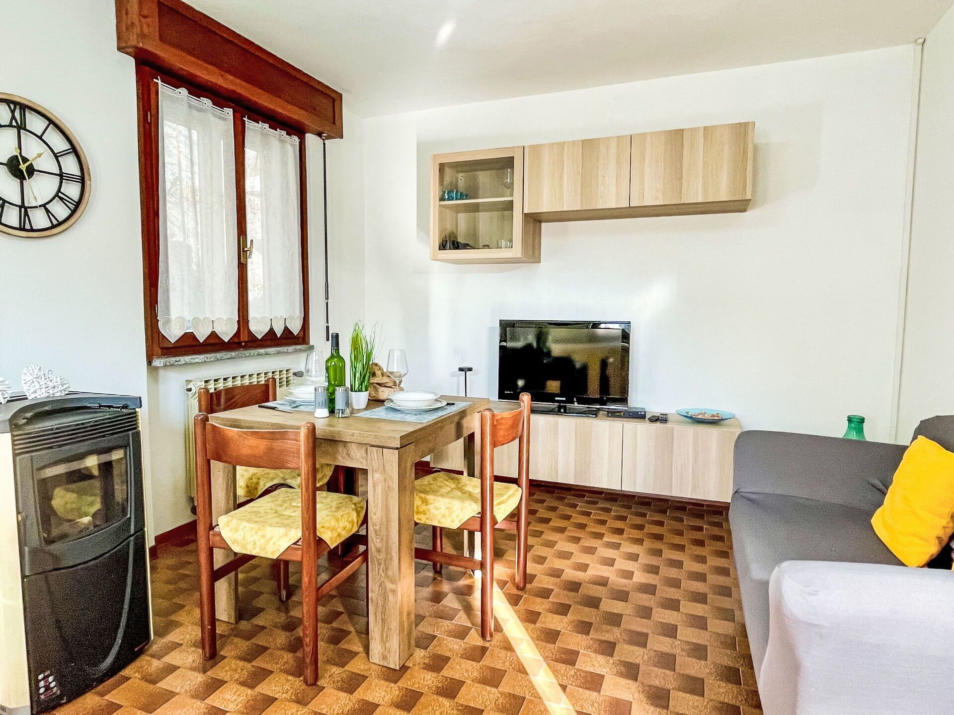 A compact living space with a dining table, chairs, a sofa, a TV, and a small kitchen area.